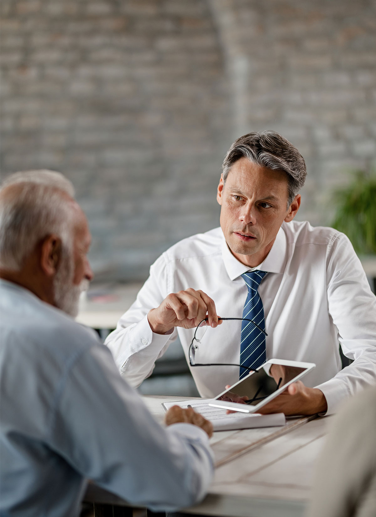 insurance-agent-communicating-with-senior-clients-while-showing-the-something-on-touchpad-during-meeting-in-the-office